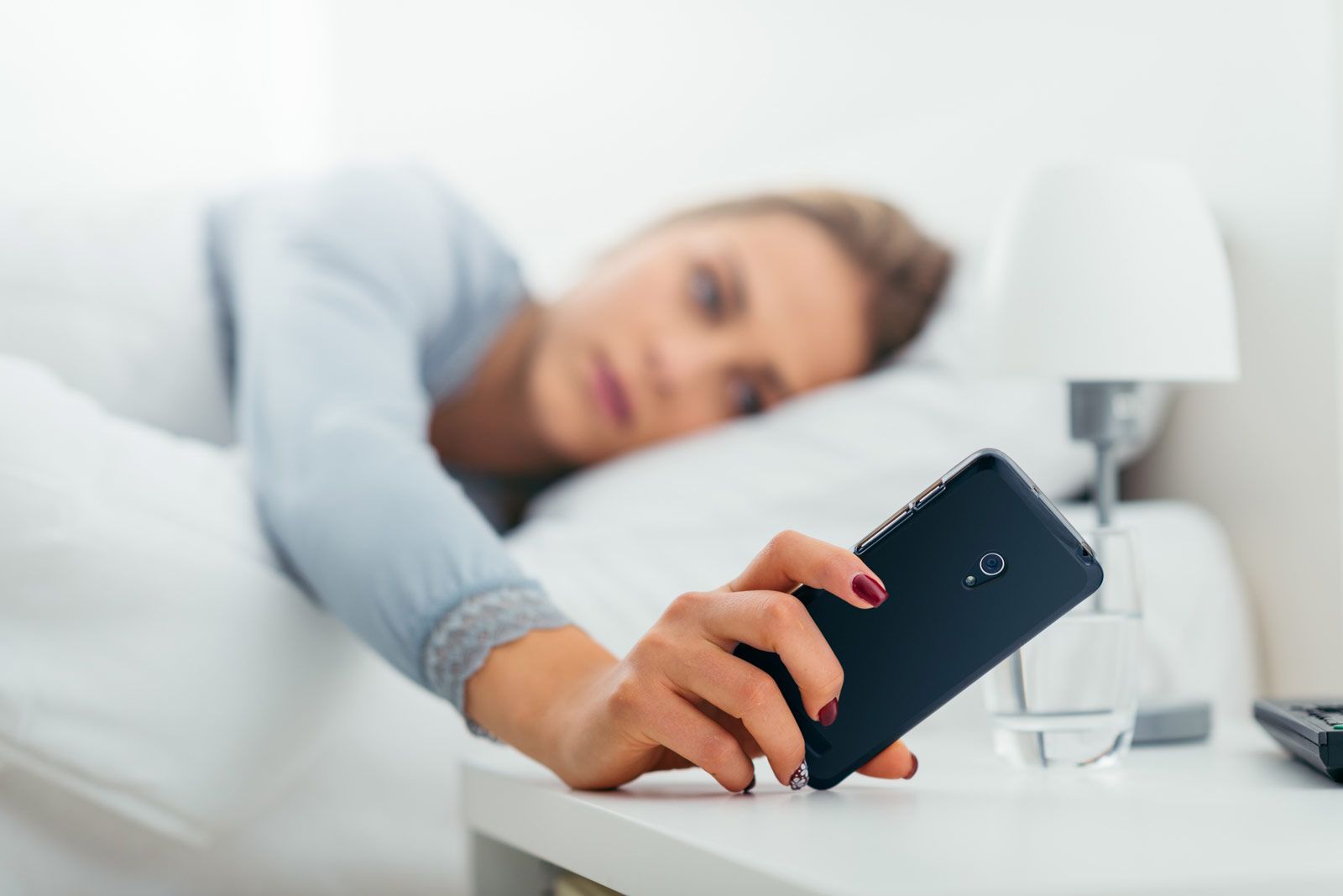 Frau mit Smartphone im Schlafzimmer